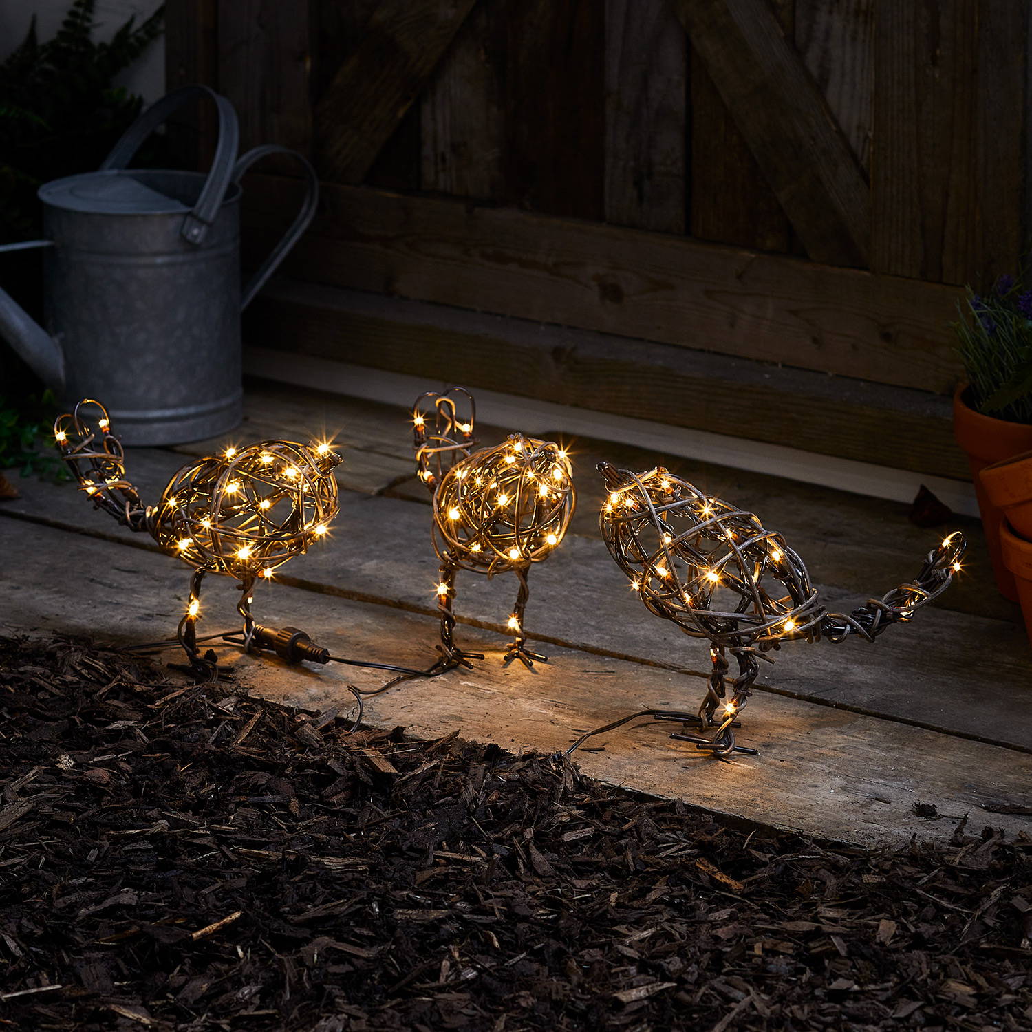 Trio of rattan birds illuminated outdoors