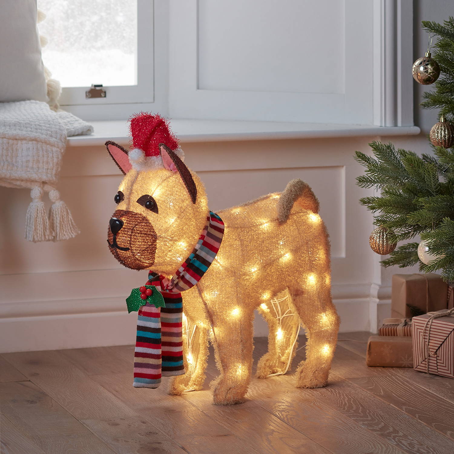 Fluffy bulldog figure standing under a Christmas tree alongside presents