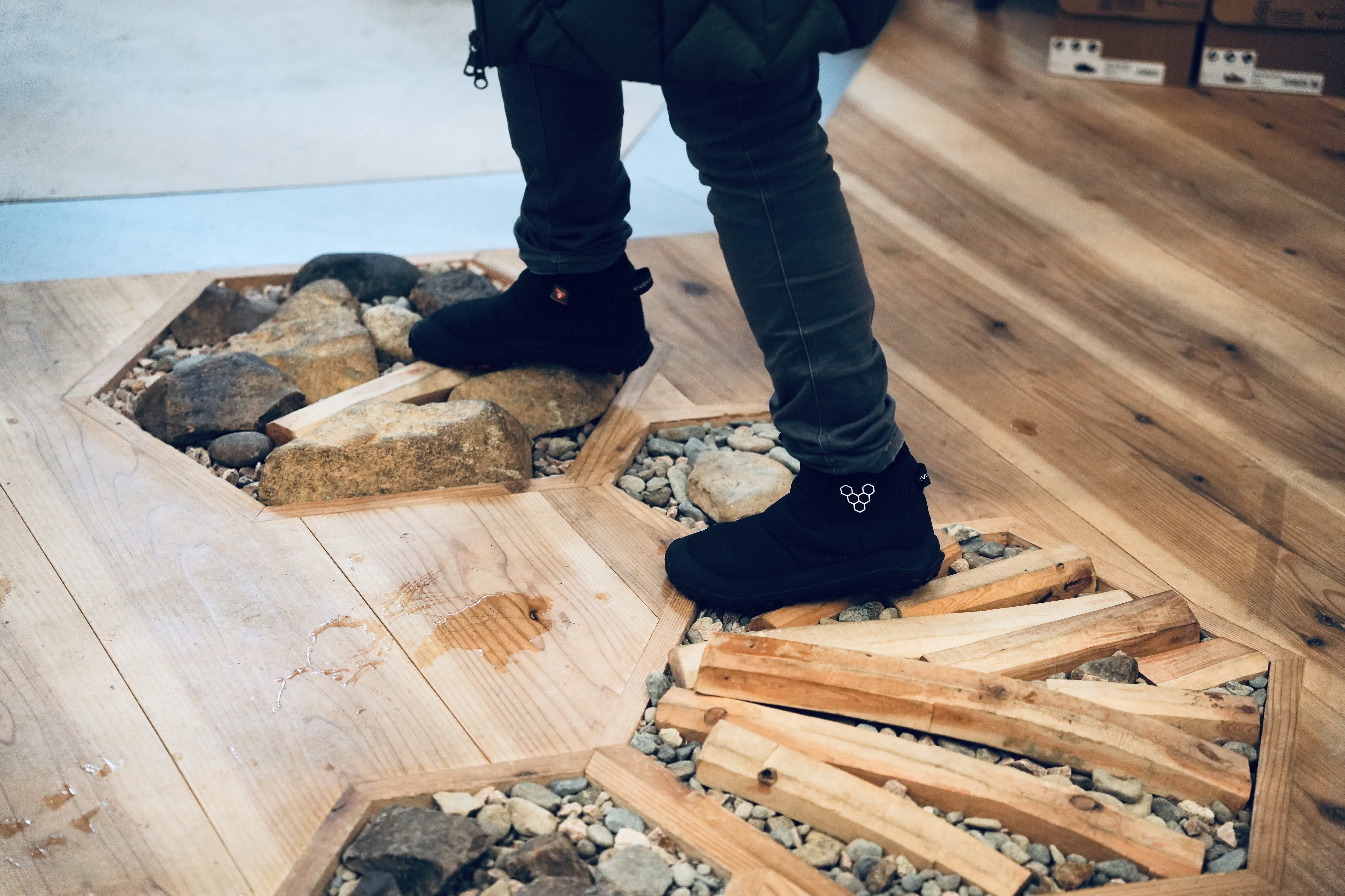 Person standing on a wooden floor with stones and wooden planks.