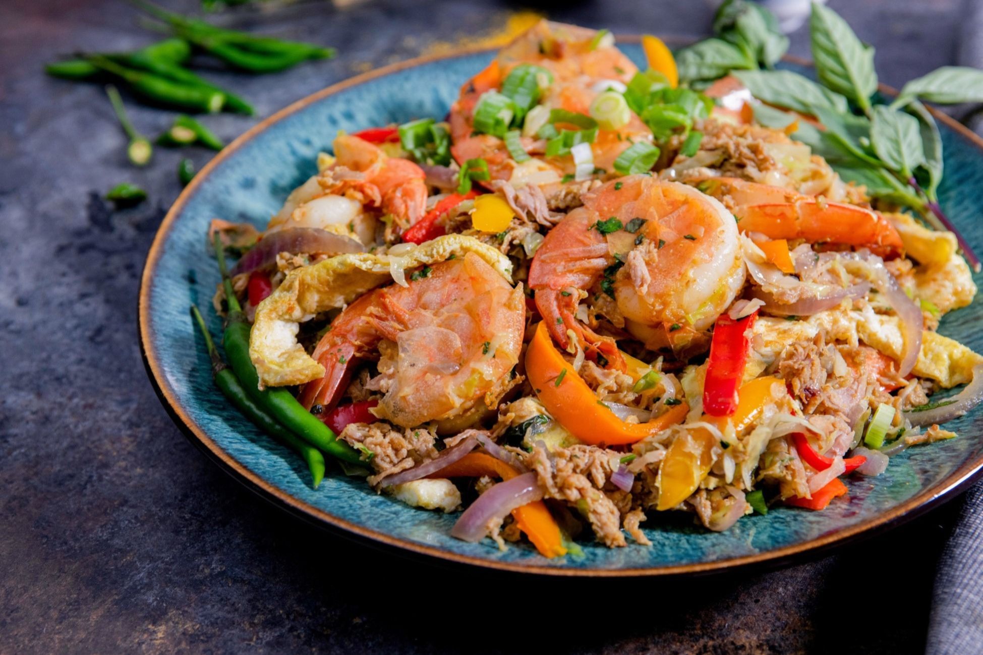 A colorful plate of shrimp stir-fry with vegetables and rice.