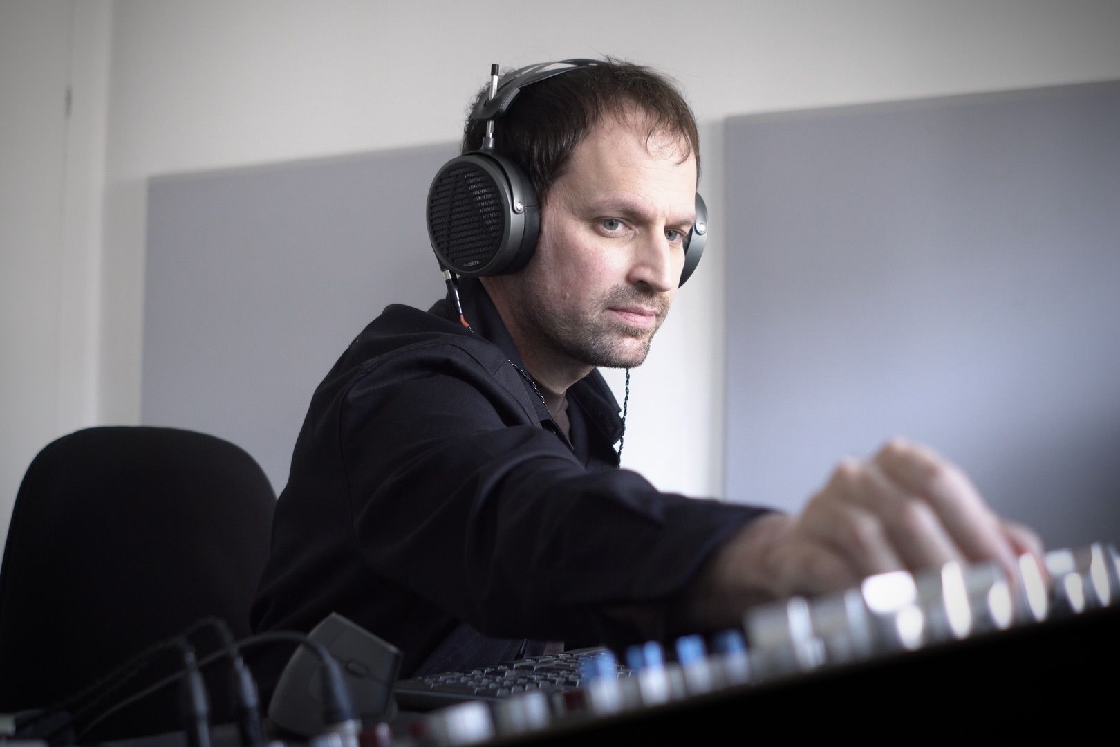 Nadav Katz wearing Audeze MM-500 headphones working on a sound mixing console.