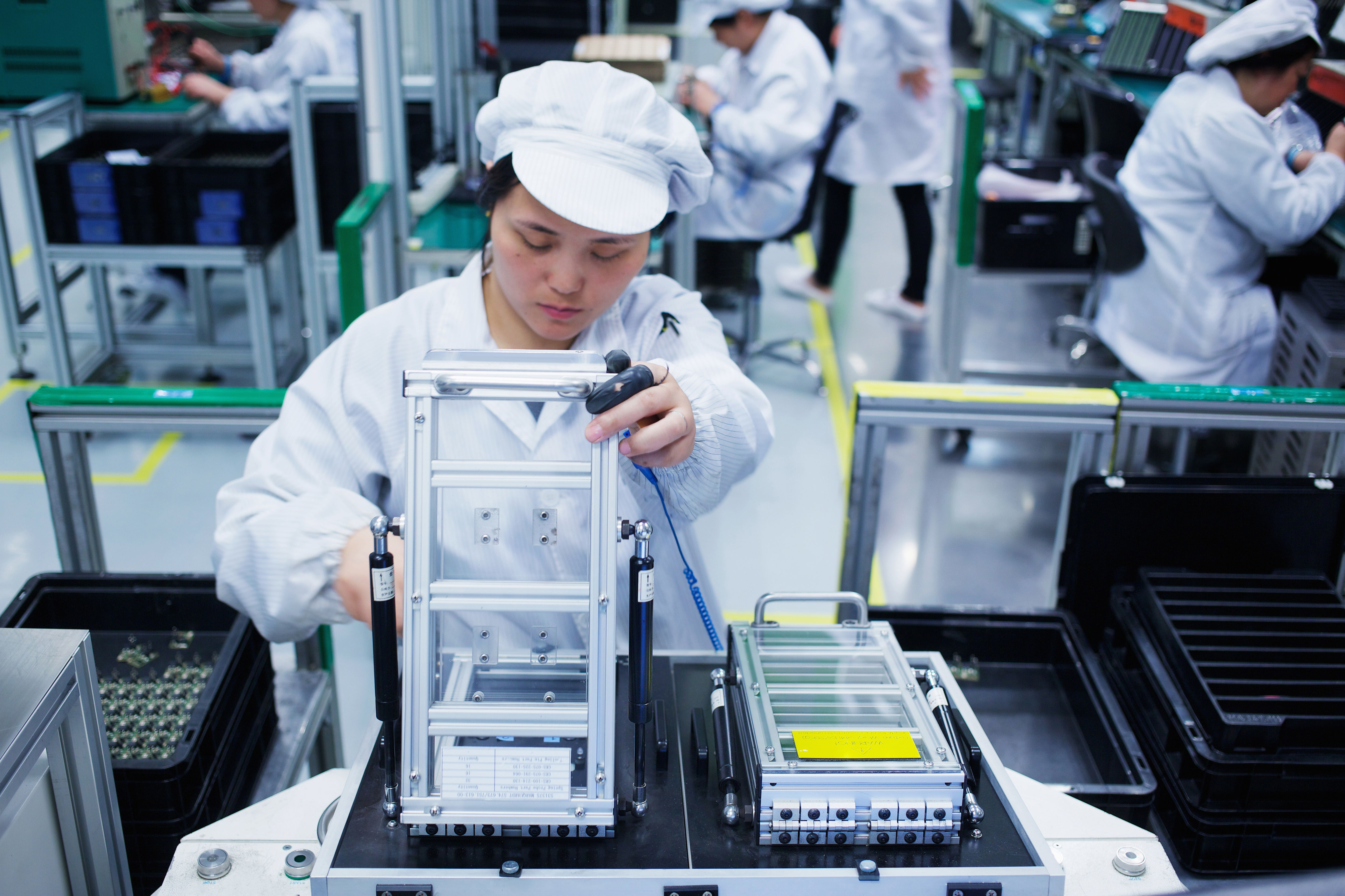 wokers at each stage of an assembly line working with small parts