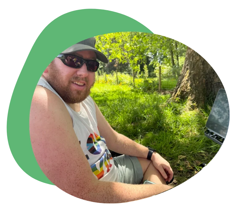 Person sitting outdoors in a tank top and sunglasses, enjoying nature.