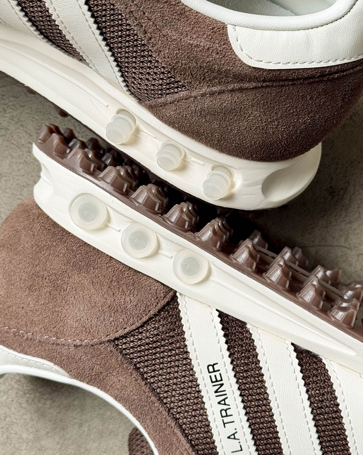 Brown Adidas sneakers with white stripes and textured detailing.