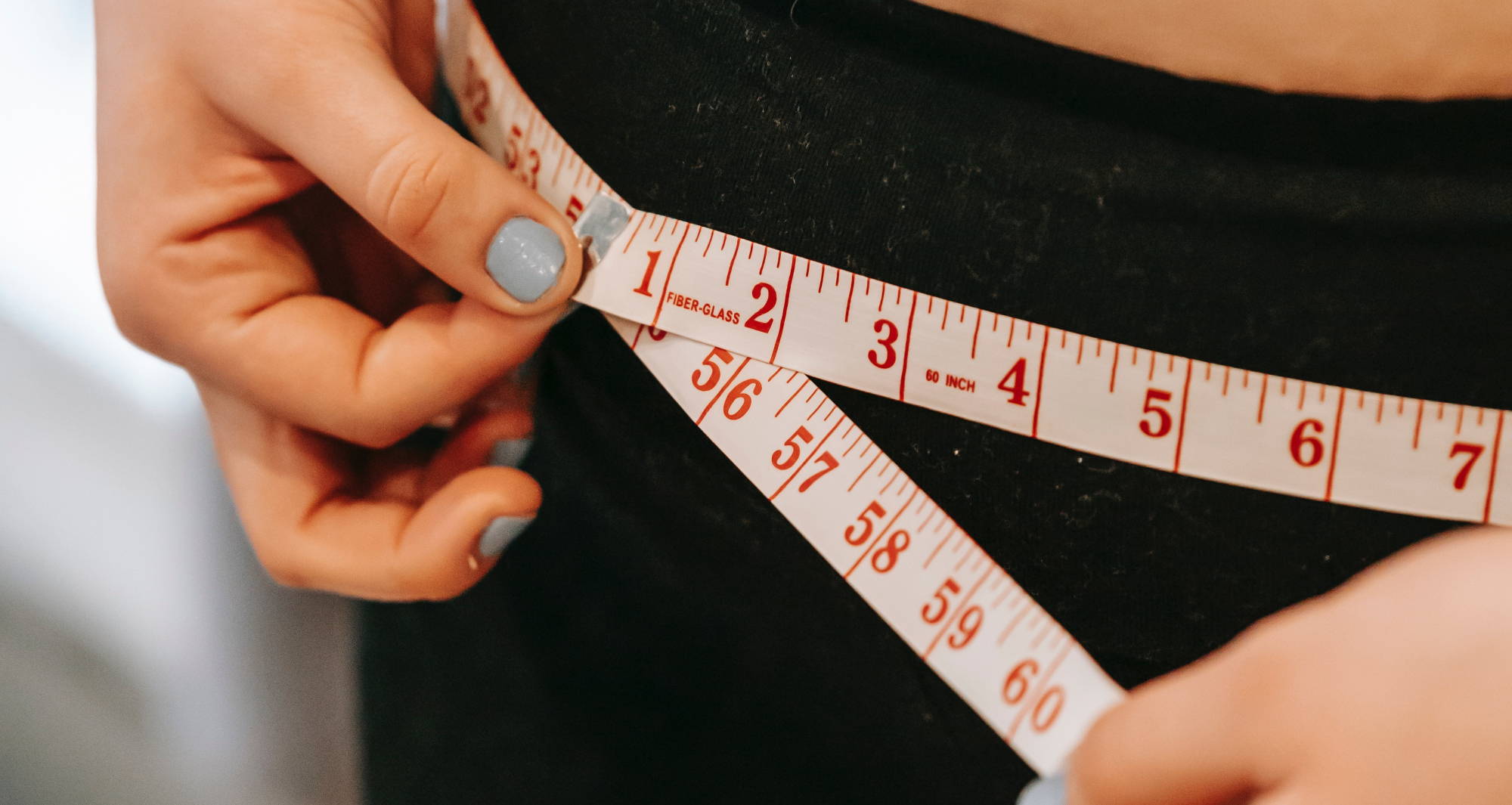 A woman measures herself as she tries to figure out what size her underwear is.