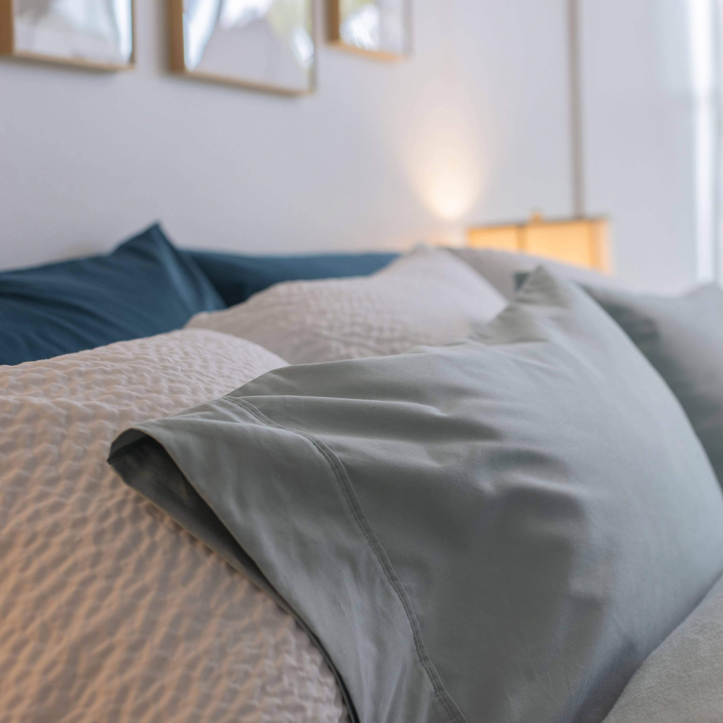 Head of a bed with three layers of pillows in pacific cotton, cumulus comfortcore and dusty blue flannel