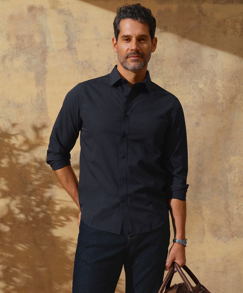 Man in a black shirt standing against a textured background.