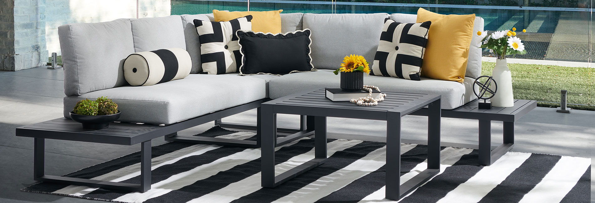 Modern outdoor seating area with cushions and a black and white rug.