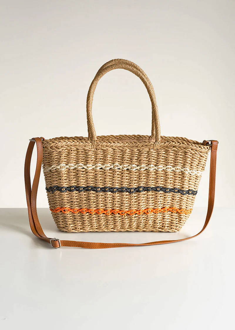 A wicker basket with white, black and orange stripes and a leather shoulder strap