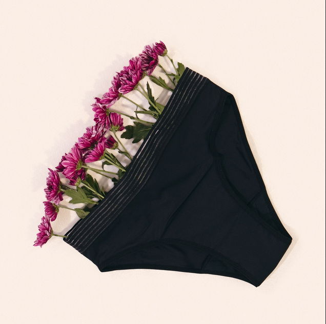 Black underwear with flowers arranged on the waistband against a light background.