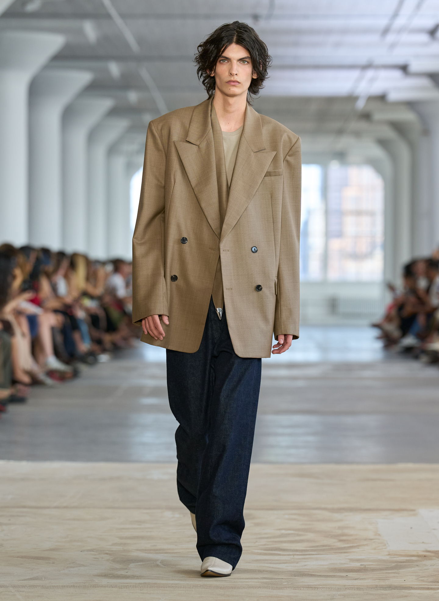 A model walking down a runway in oversized fashion attire.