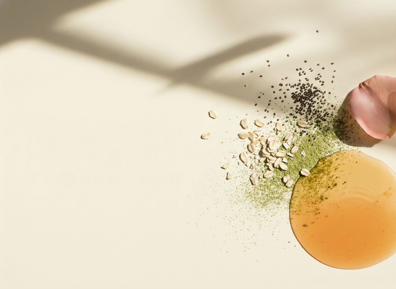 A hand dropping spices onto a surface with an orange liquid.