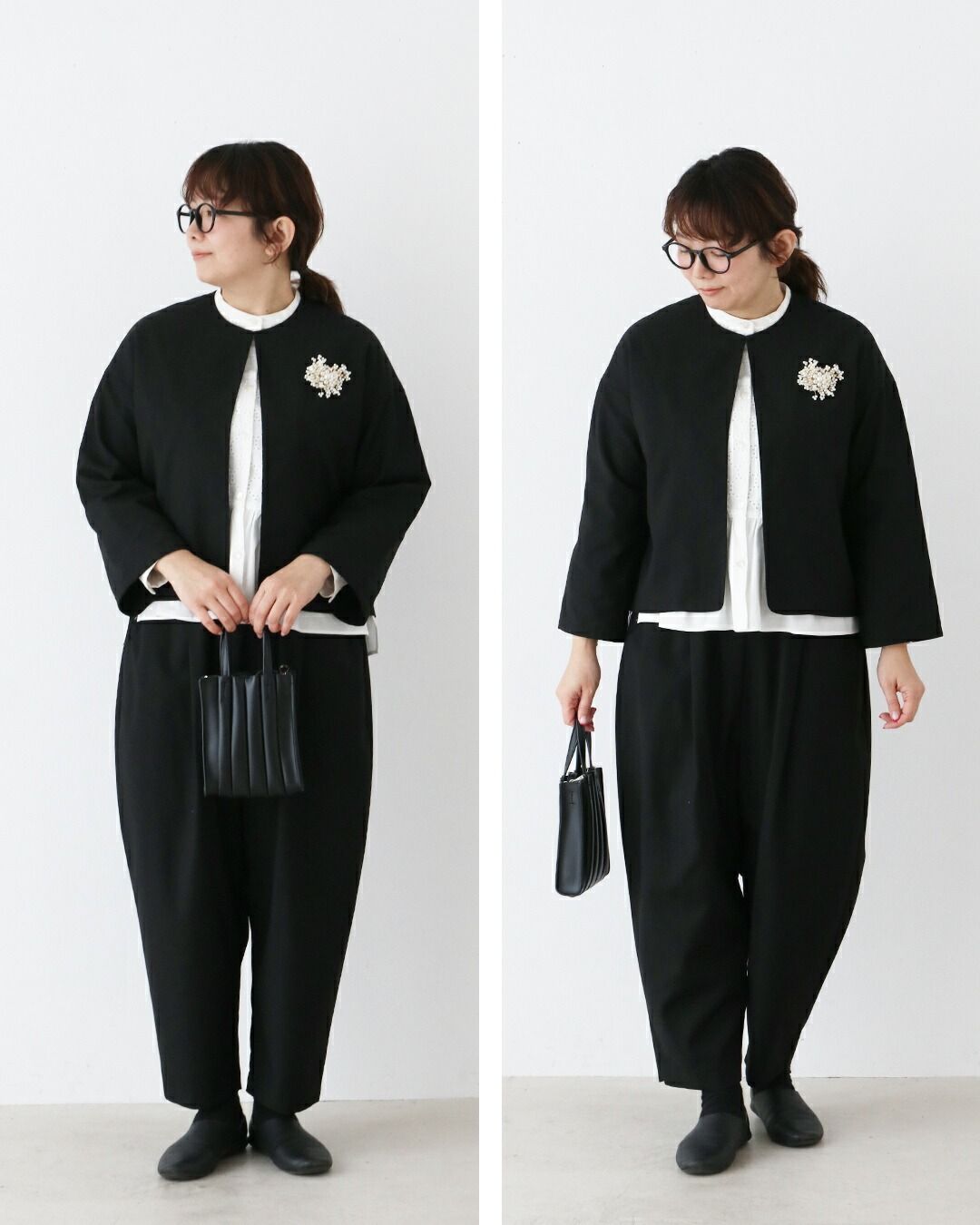 Woman in black outfit poses with a handbag against a white background.