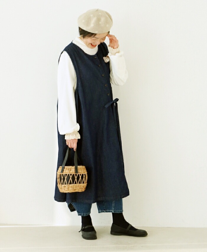 Woman wearing a navy dress, white top, and a beret, holding a basket.