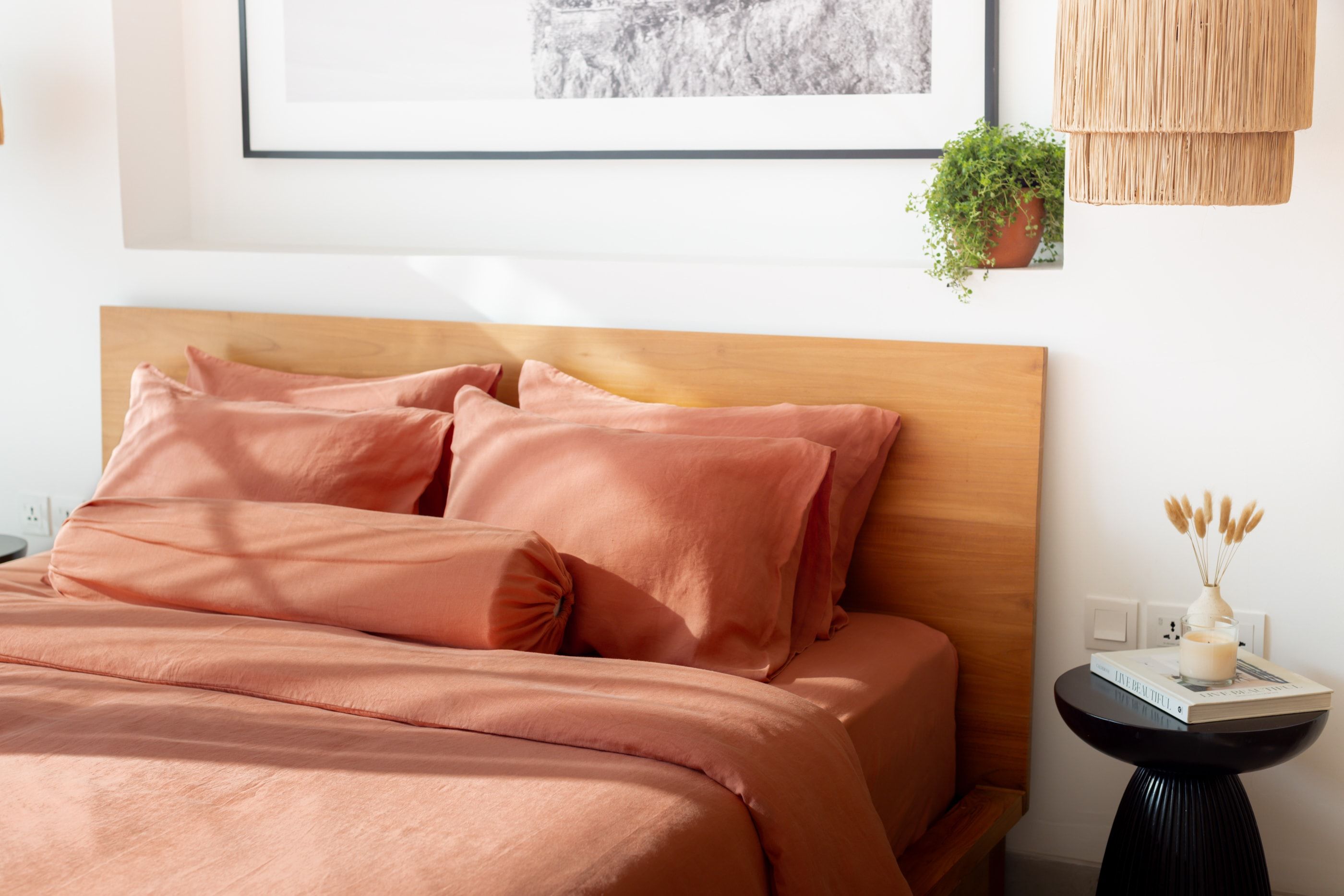 terracotta linen bedsheets against a wooden headboard with a black coffee table next to it