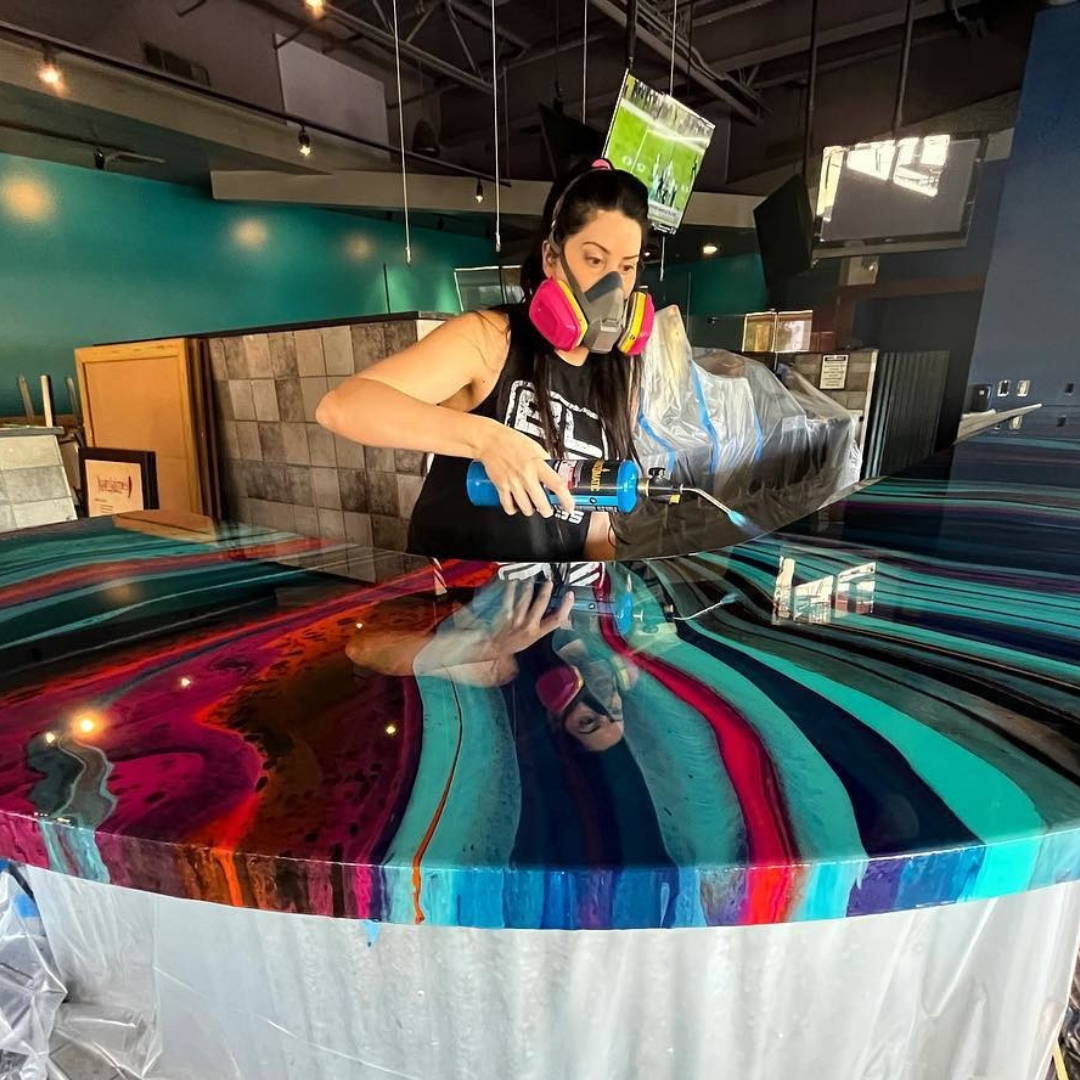 resin artist leila parnian using a blow torch to get bubbles out of her dirty pour bar top for a local business