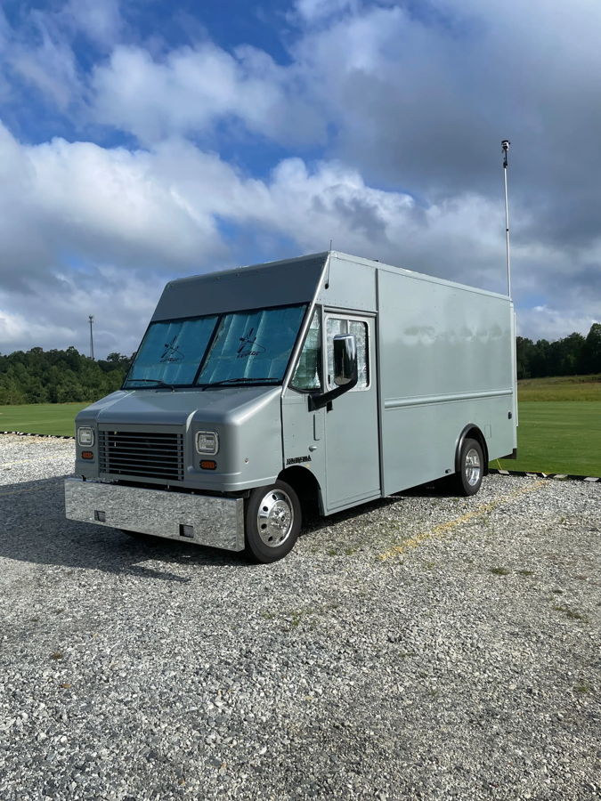 Front three-quarter Bryan's Ford E-450 Utilimaster grey step van with chrome bumper parked on gravel photo 1