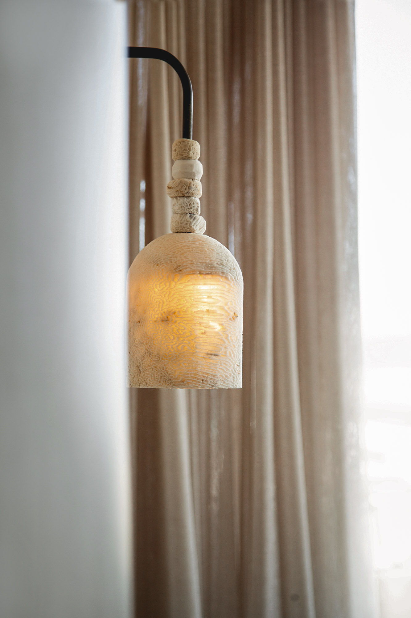 Fossil coral arc dome wall light next to sheer curtains.