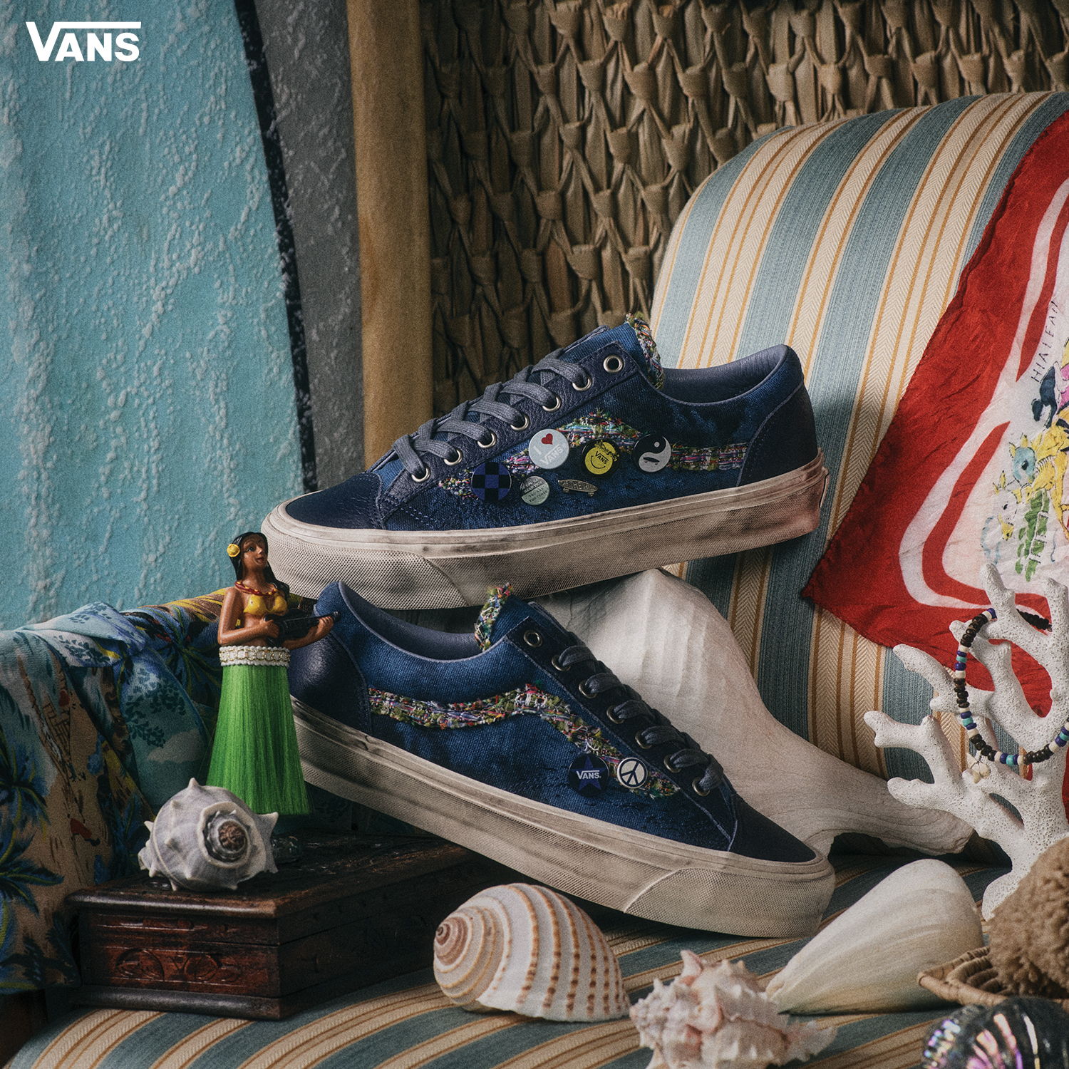 Blue Vans sneakers with colorful embellishments on a striped chair.