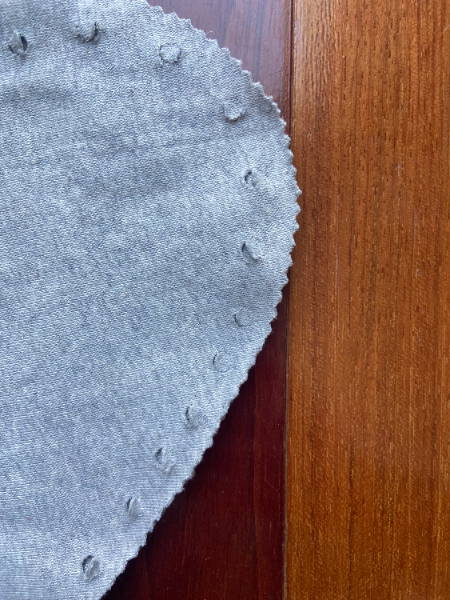 close up of punched holes in gray jersey knit fabric.