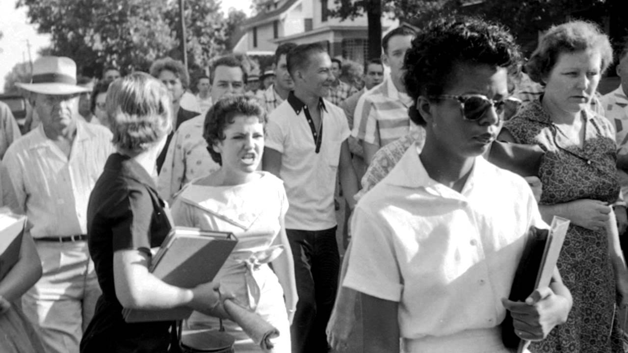 An African American student carrying her school books into a newly integrated school in 1957