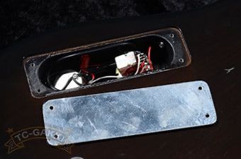 A metal cover over an opening revealing electrical components inside.