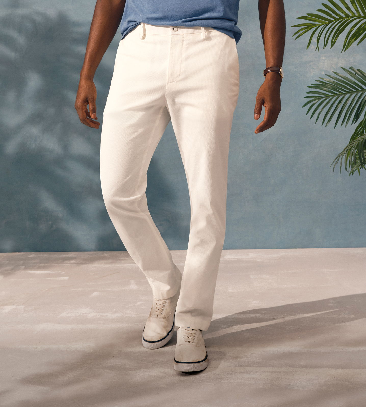 A person wearing white pants and a blue shirt standing on a light surface.