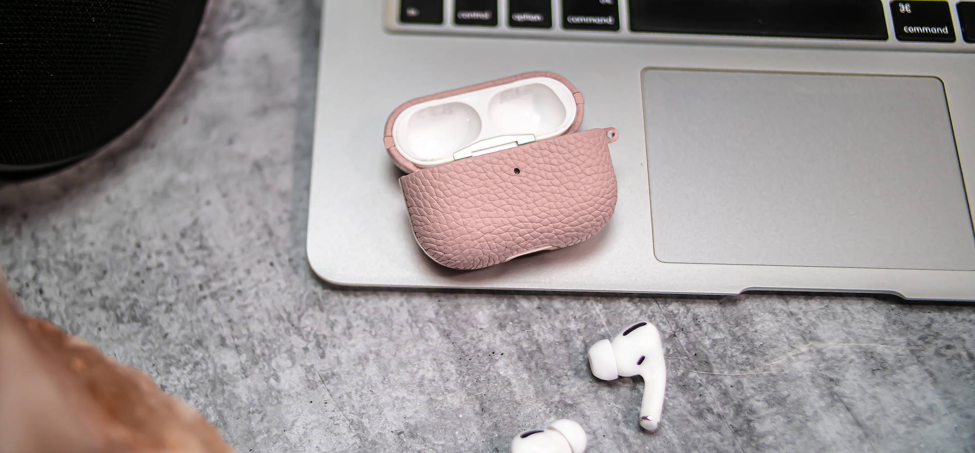 pink genuine leather airpods pro case laying on a macbook with the lid open