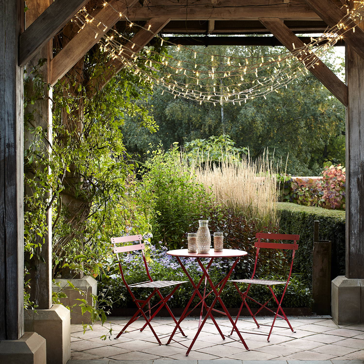 Warm white fairy lights handing from a  pergola above an alfresco café table 