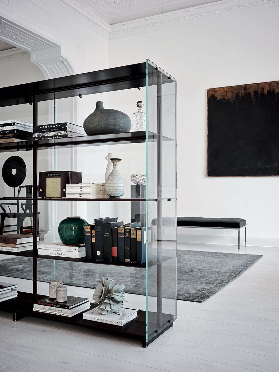 Modern bookshelf with decor items, white walls, and a stylish chair.