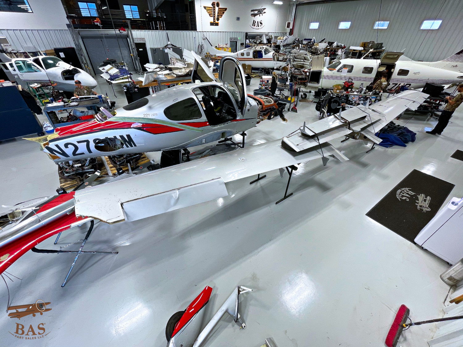 Aircraft being assembled in a spacious hangar with various tools and parts.
