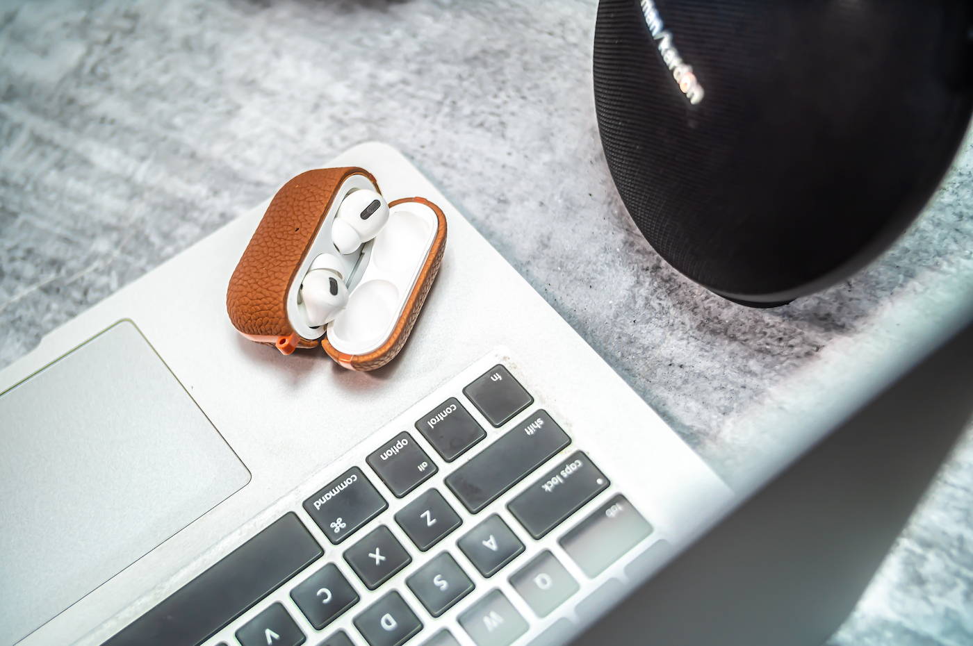 brown genuine leather airpods pro case laying on a macbook with open lid