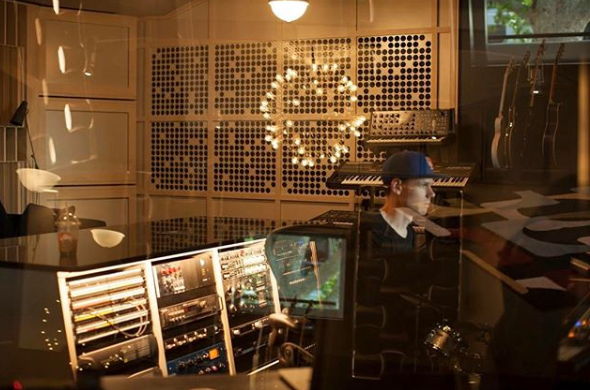 Person working in a music studio with sound equipment and illuminated background.