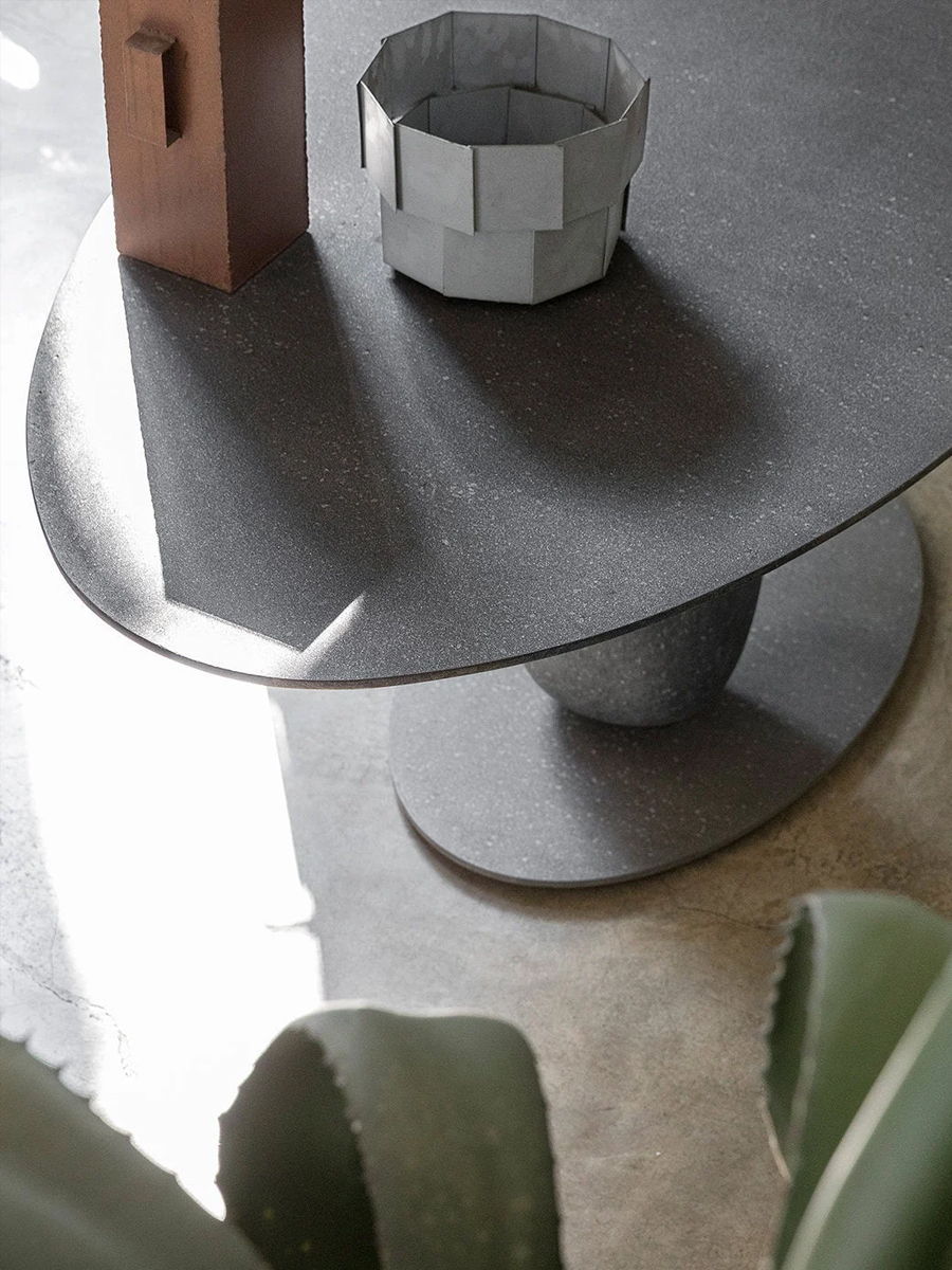 A modern Matera Mogg table with decorative objects and green plants nearby.