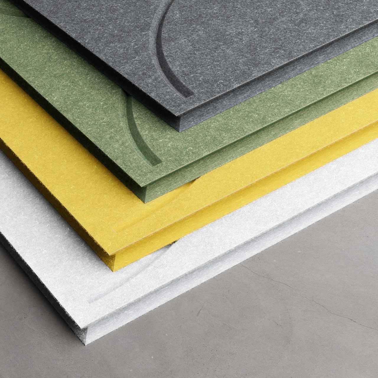 Assorted-colored soft felt panels for the ofinto Cubox shelving system, featuring curved design grooves, stacked one above the other in a fan-like pattern in light gray, yellow, green, and anthracite.