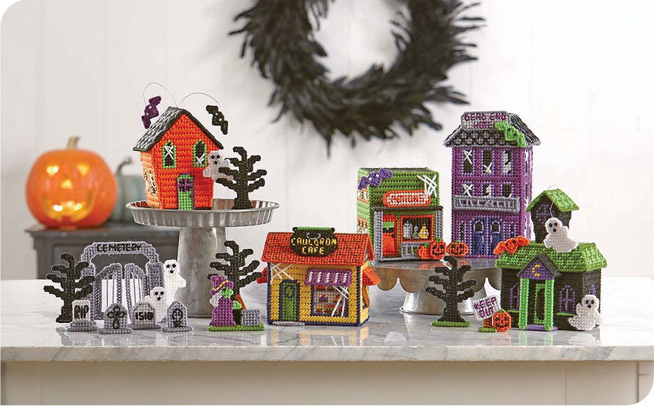 Colorful Halloween decorations featuring houses, trees, and a carved pumpkin.
