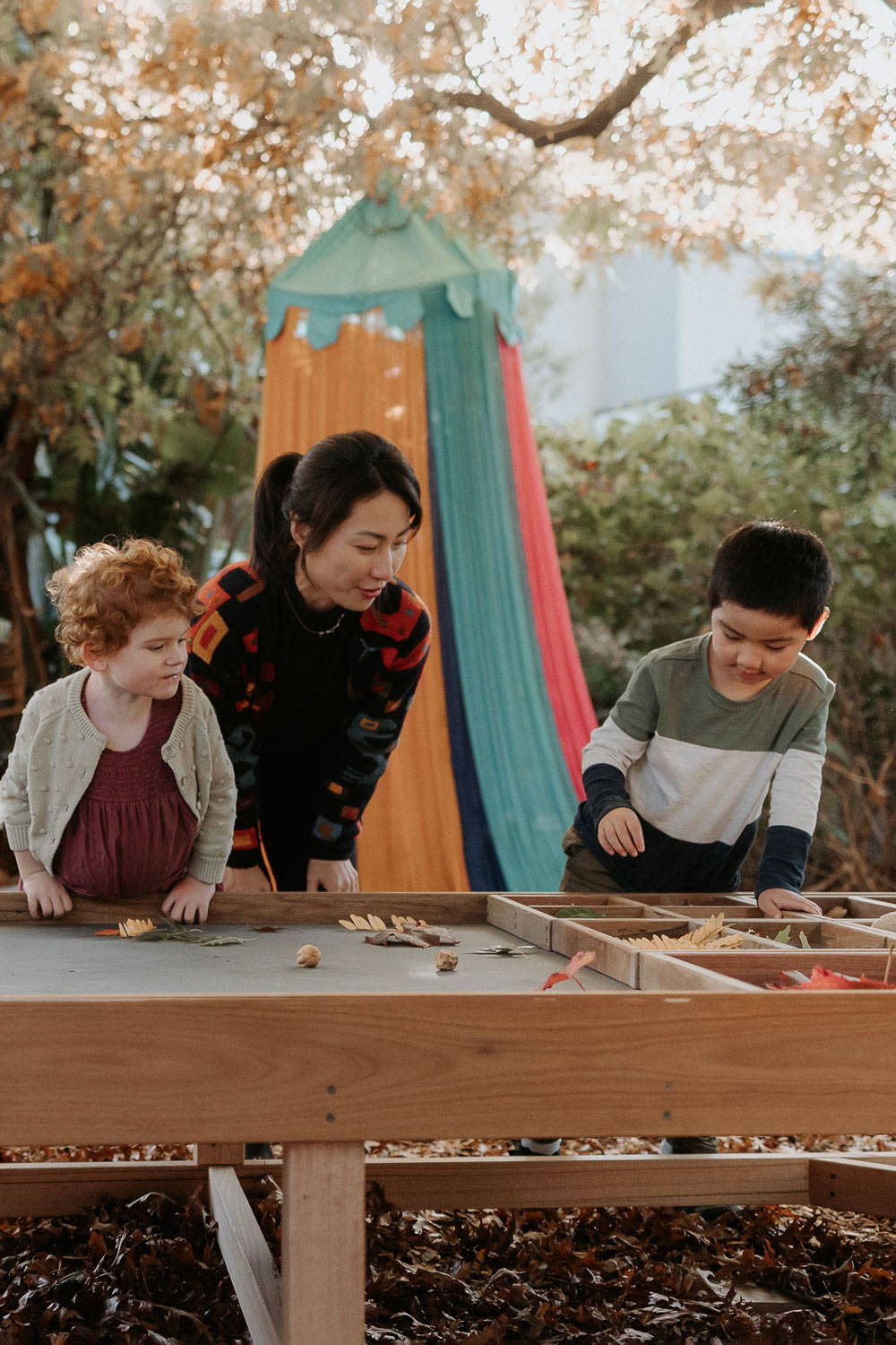 Woman Nuturing Children Engaged in Sensory Play at the Sensory Play Table