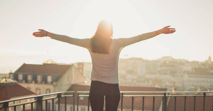 Woman In White Sleeve Shirt Standing With Arms Open Looking At The Sun