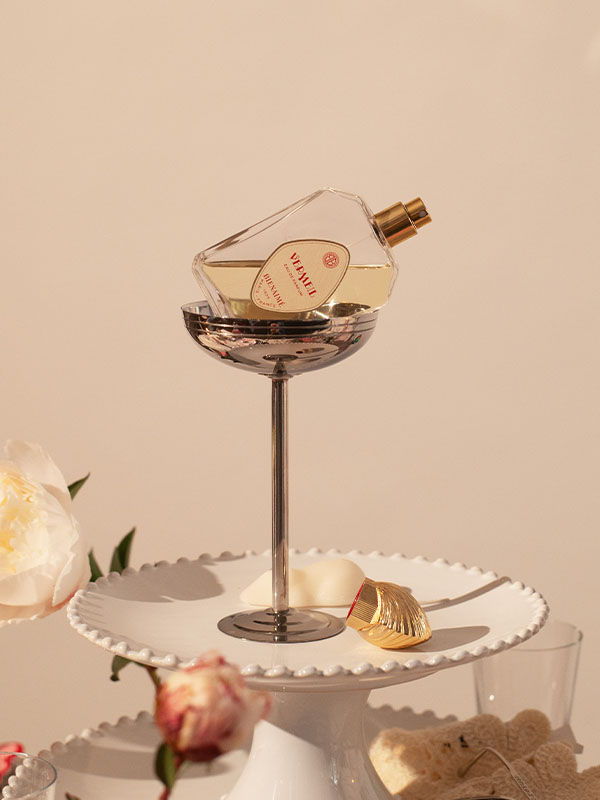 A perfume bottle displayed on a decorative stand with flowers.