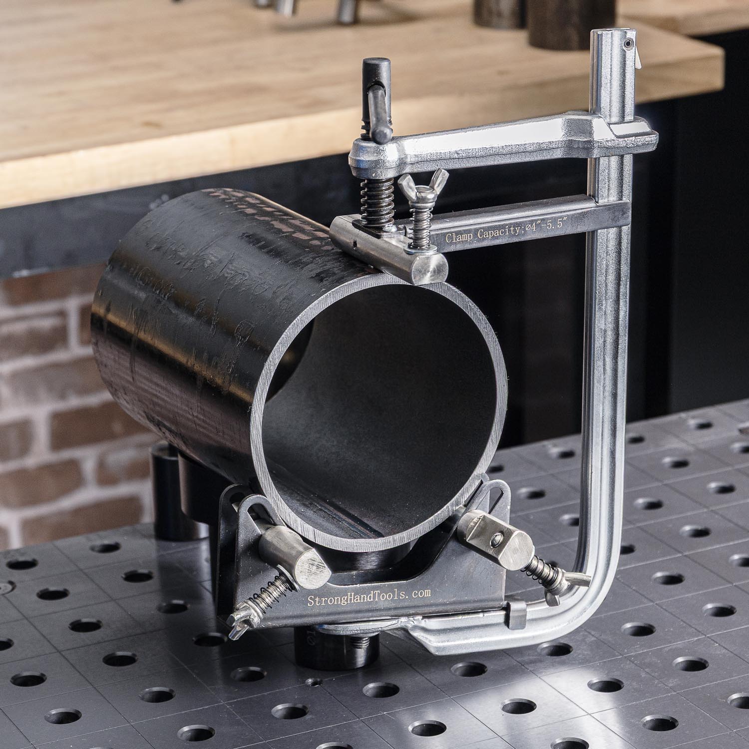 Metal pipe clamp on a workbench with a perforated surface.