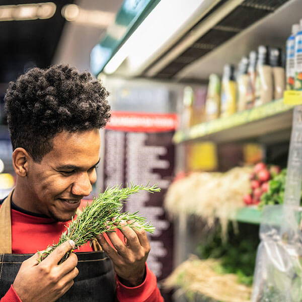 High Quality Organics Express Man smelling fresh rosemary at the store