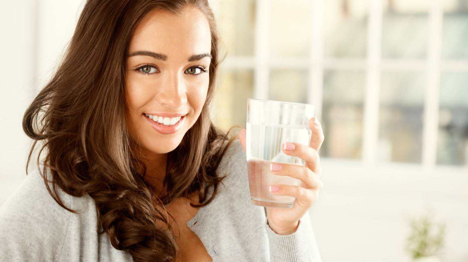 Attractive young woman drinking water at home | Health Benefits Of Morning Water Therapy  | Featured