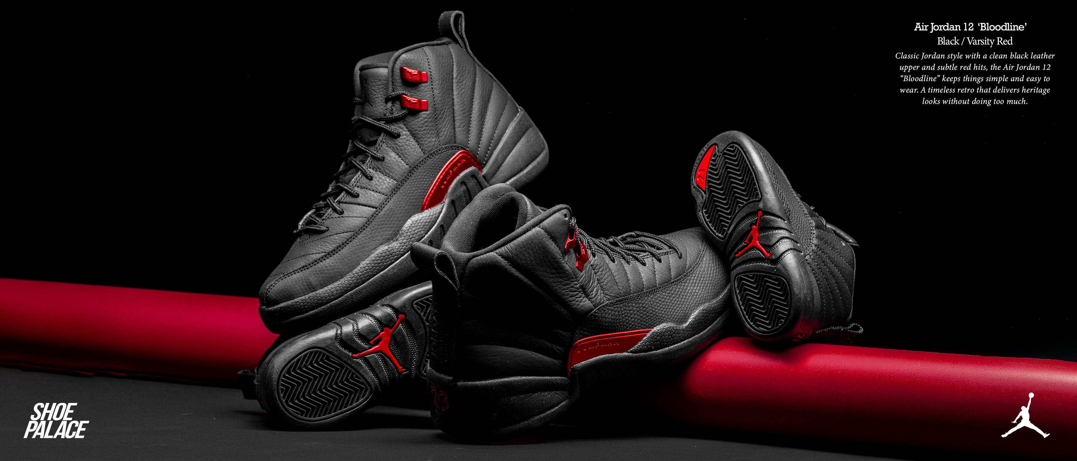 Black and red basketball shoes displayed on a red surface.