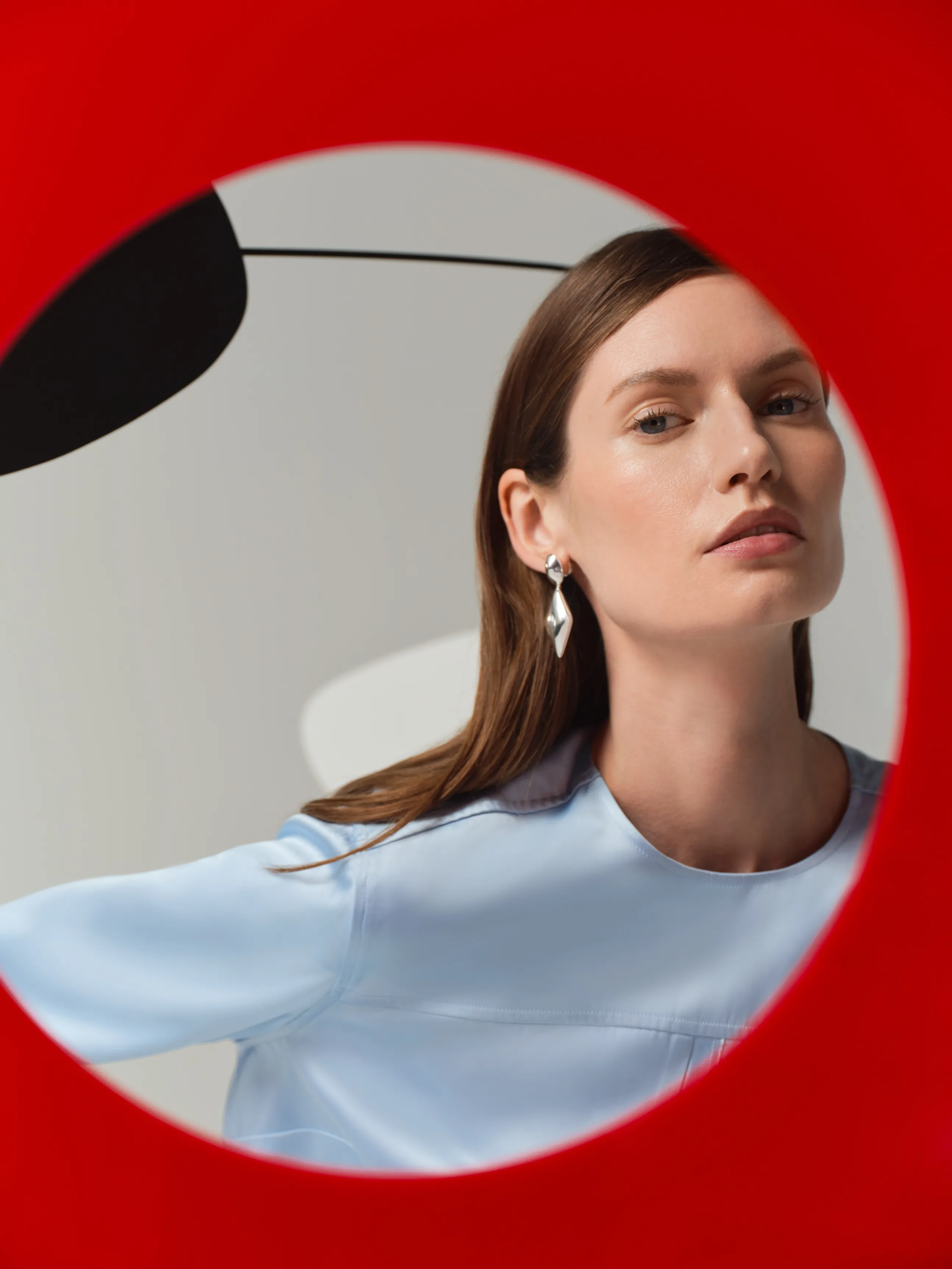 A woman in a blue shirt poses through a circular red frame.