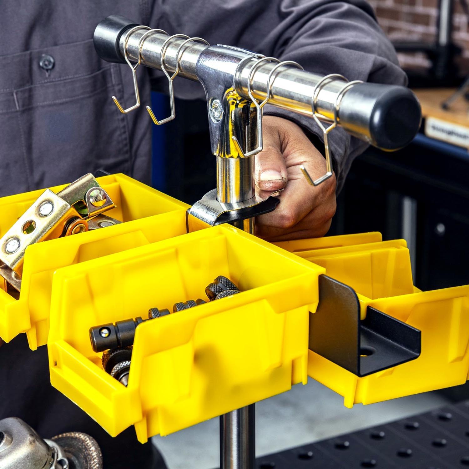 A person organizing tools in yellow storage bins on a workbench.