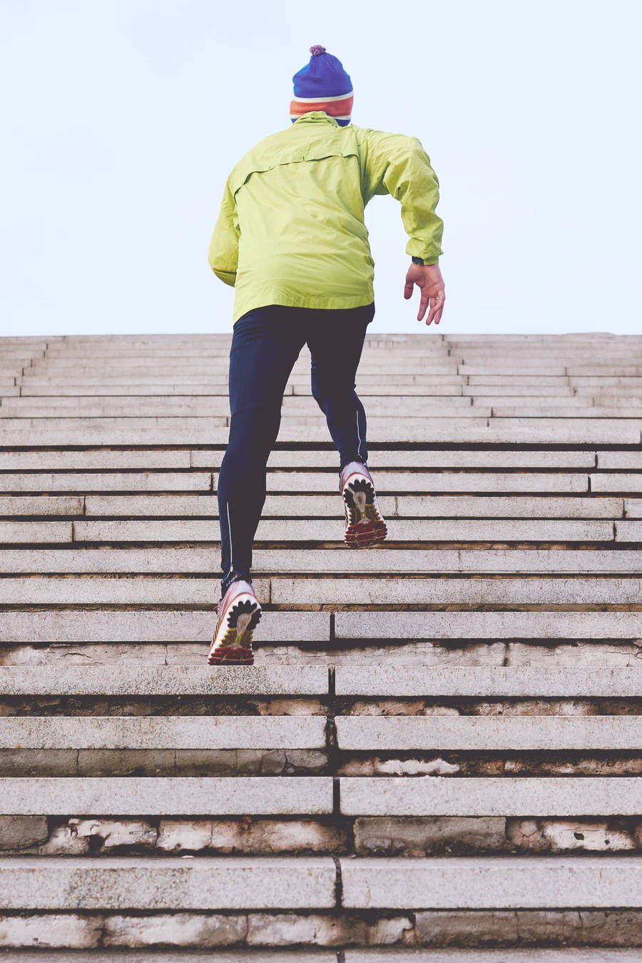 Man in green jacket running during winter. Man in winter training. 