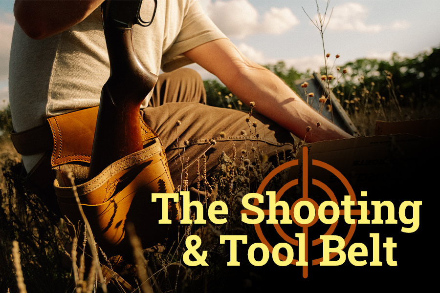A person with a rifle wearing a shooting and tool belt.