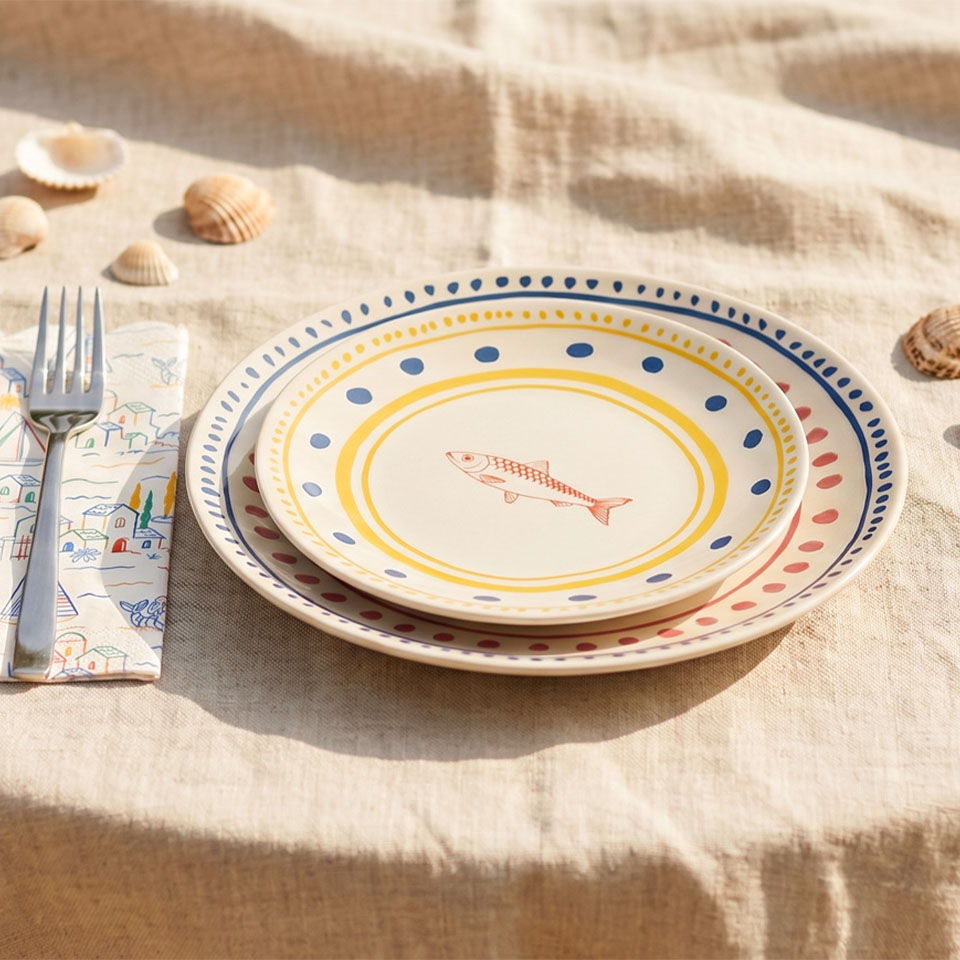 Stack of decorative plates with a fork and napkin on a table.