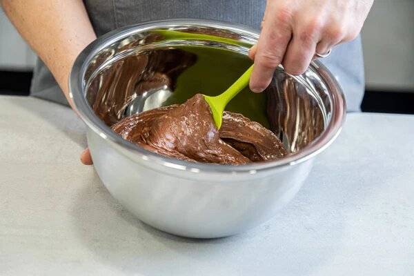 Chocolate cake batter being mixed in a bowl with a spatula.
