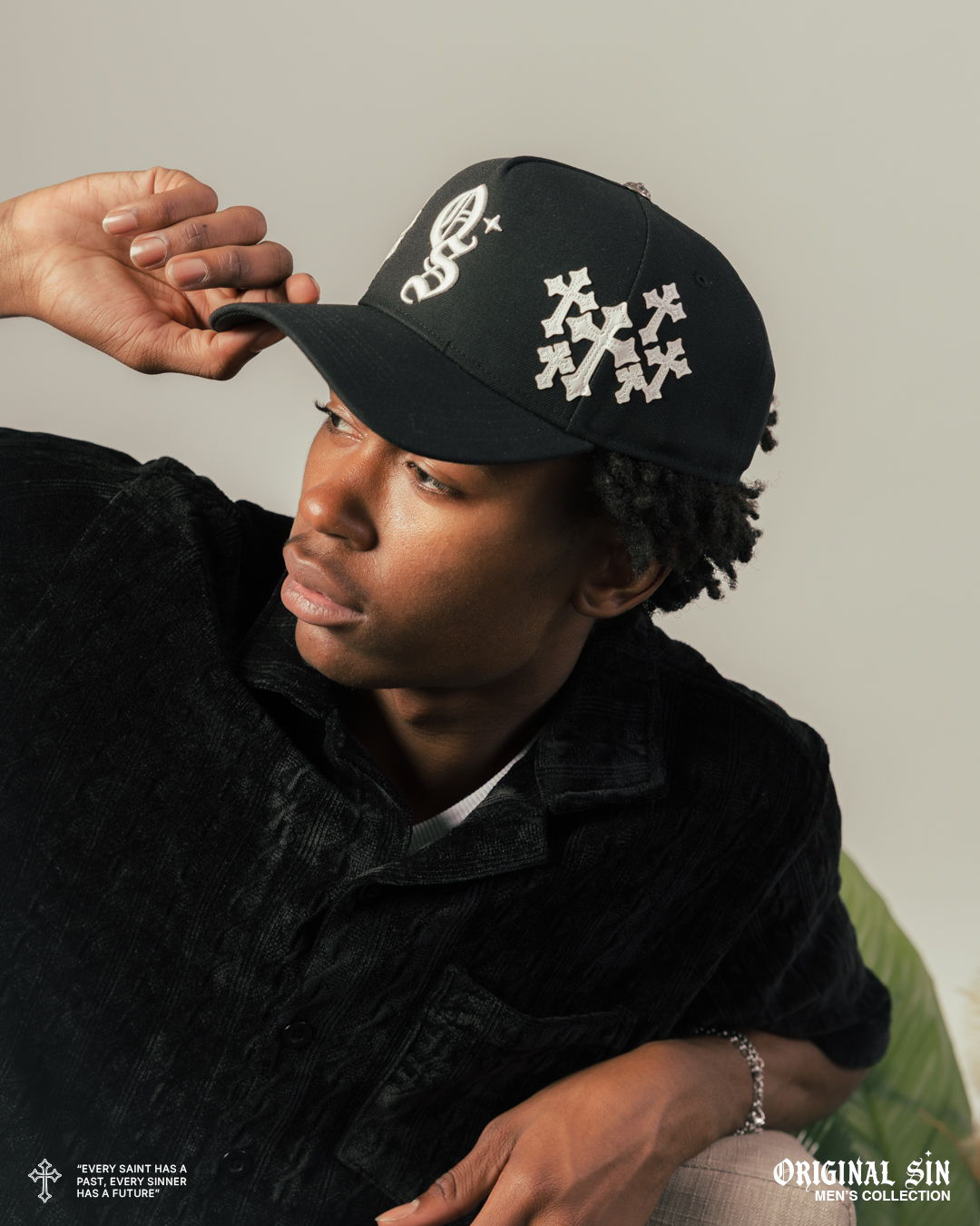 Young man in a black cap, looking thoughtfully while seated.